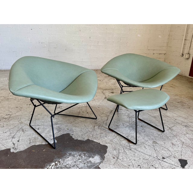 Beautifully upholstered in pebbled leather in a muted teal green on this 3-piece black wire lounge chair and ottoman set....