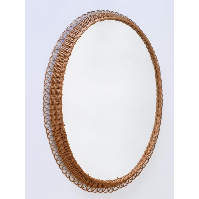Highly decorative and rare mid-century modern oval wall mirror. manufactured in germany, 1960s. executed in rattan and...