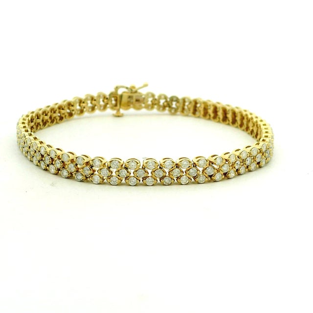 An elegant three-row diamond bracelet crafted in 14-karat yellow gold and set with 156 round brilliant-cut diamonds...