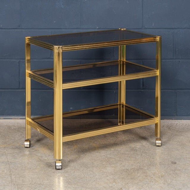A refined French drinks trolley attributed to Maison Jansen, dating from the 1970s, featuring a gilt brass frame with...