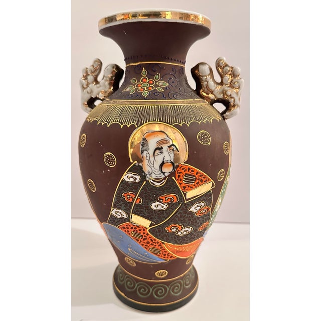 A dark brown-ground Satsuma-style vase with hand-painted figures set in gilt-framed medallions around the body. Each...
