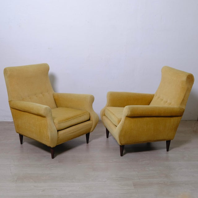 A pair of beautiful yellow fabric Bergere armchairs dating back to the 1960s and featuring typical conical wooden legs....