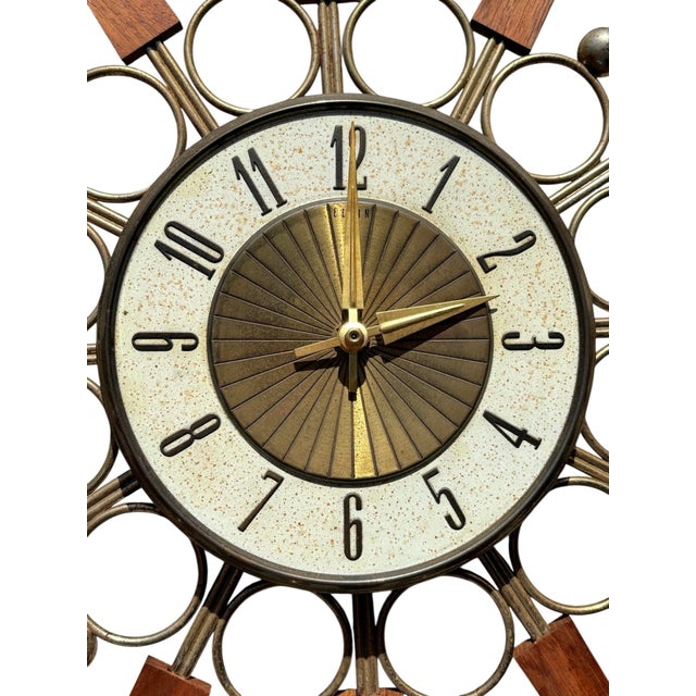 A Danish mid century modern atomic style sunburst wall clock made by Elgin National Watch Company. A brass frame supports...