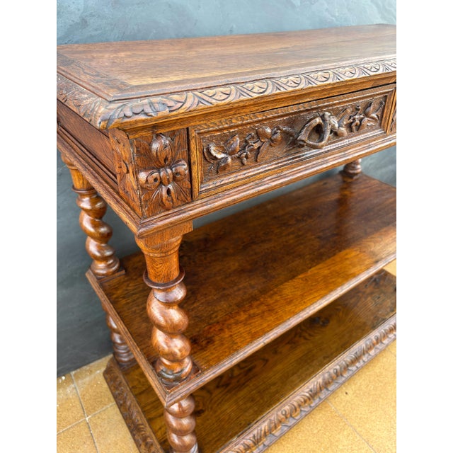 Antique carved oak console table featuring finely turned barley twist legs and rich floral carving to the apron. The piece...