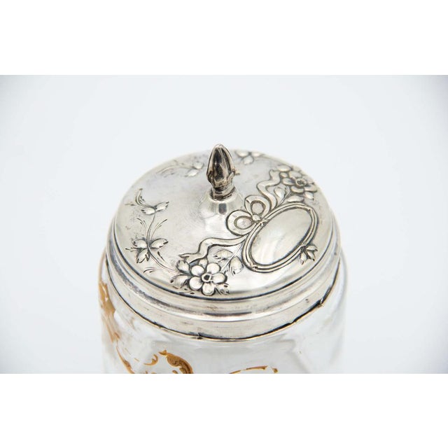 Cut and Gold-Painted Glass Bottle with a Silver Lid Featuring Embossed Floral Motifs, in Good conditions.