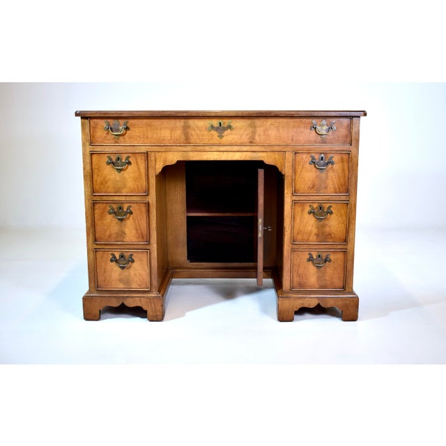 Mahogany kneehole desk with banded drawers, one long drawer over a shallow recessed cupboard with one shelf, flanked by...