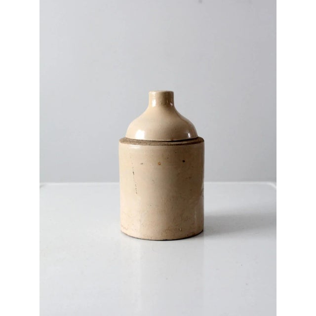 Antique American stoneware jug with a classic utilitarian form, featuring a one-gallon capacity. The surface shows a...
