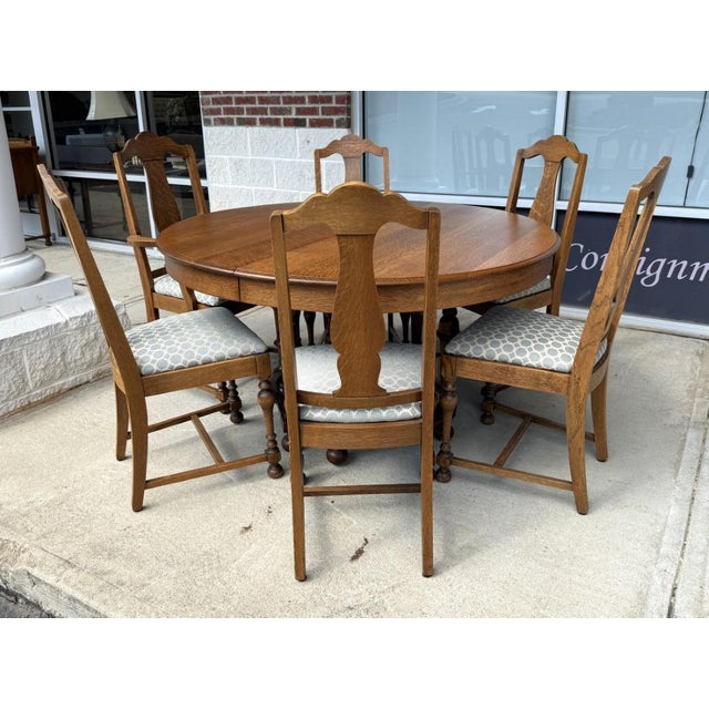 This seven-piece antique oak dining set, crafted by J.B. Van Sciver Co. in Camden, NJ, includes a substantial round table...