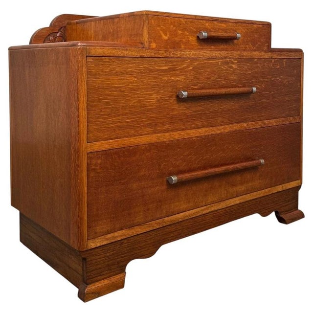 A handsome vintage 20th-century English low chest of drawers, finely crafted from oak and distinguished by its compact...
