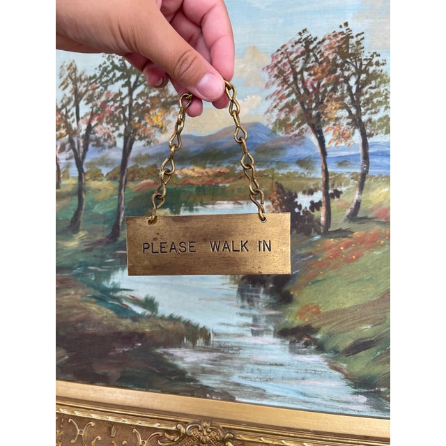 This antique brass toned door sign reads "PLEASE WALK IN" in clean, stamped lettering and features an aged patina...