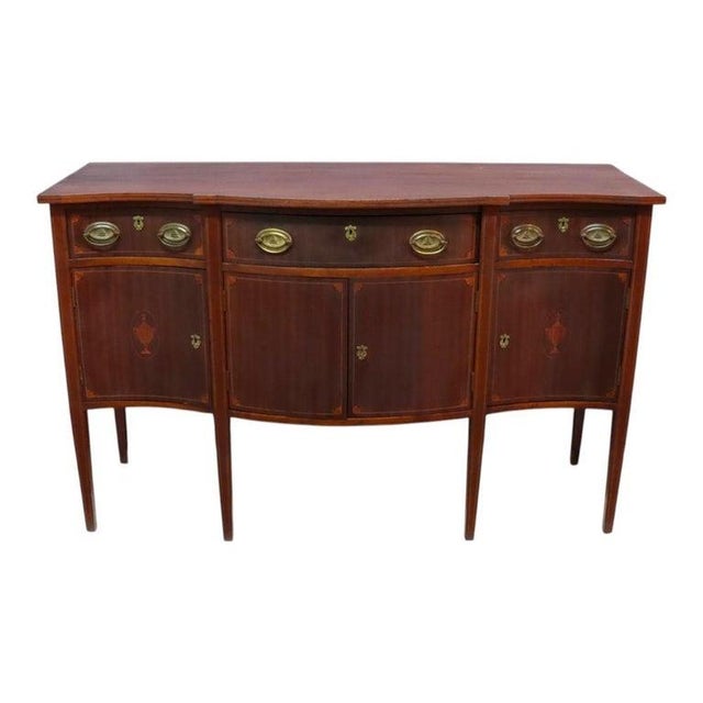 An antique English sideboard crafted in the Hepplewhite style, dating to approximately 1920. This piece is constructed...