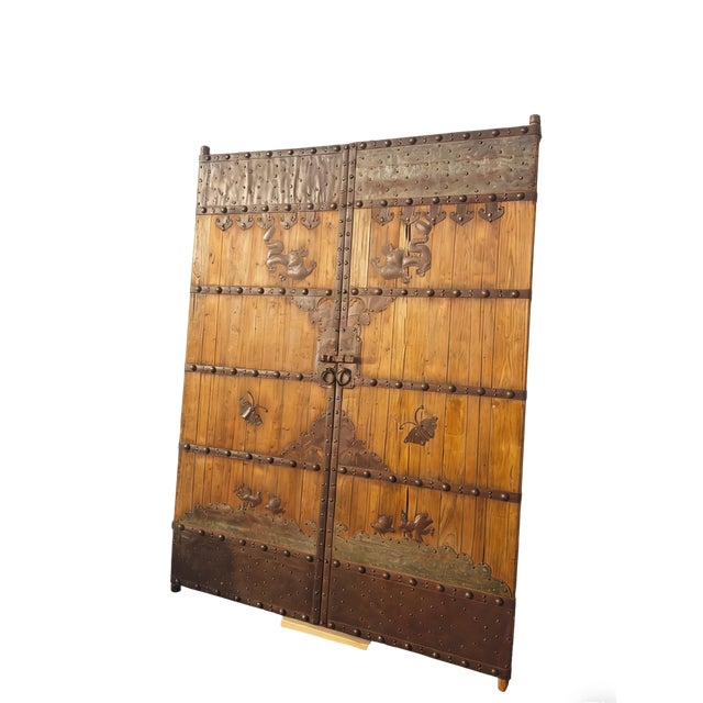 This pair of antique Chinese door panels showcase a blend of rustic wood and hand-forged ironwork. Adorned with...