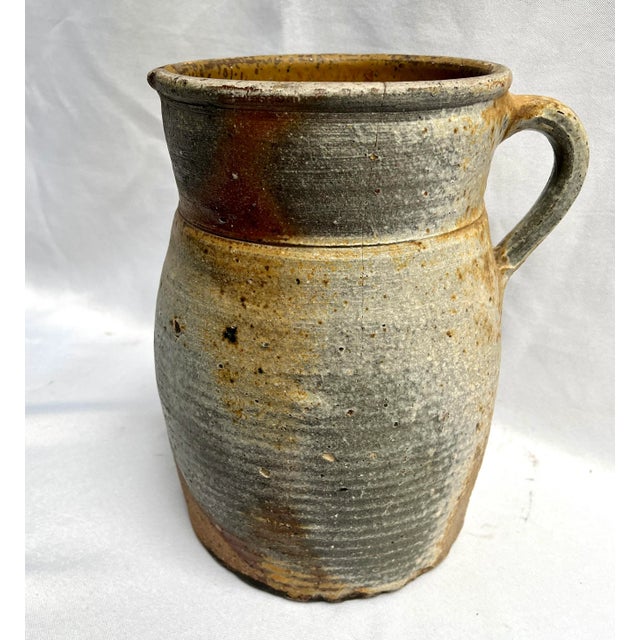 Imported from the Burgundy region of France. Early 1900s rustic hand turned pottery pitcher. Dripped glaze in neutral...
