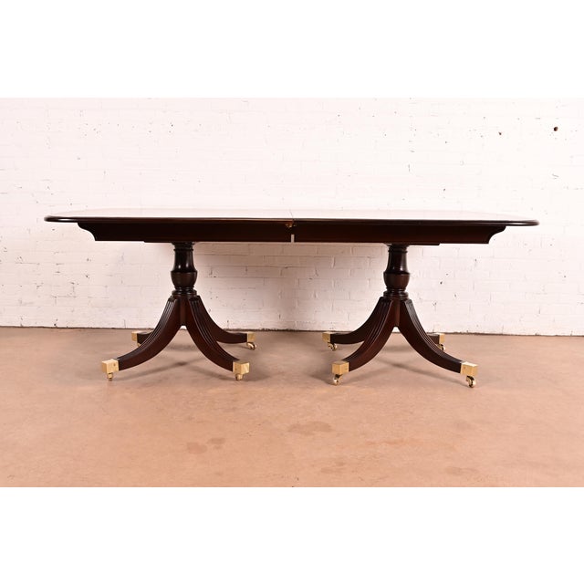A gorgeous Regency or Georgian style double pedestal extension dining table By Smith & Watson USA, Circa Mid-20th Century...