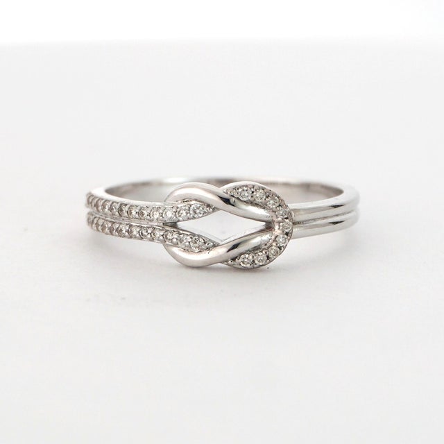 Elegant and Timeless. Set with Round White Diamonds Accented by a Graceful Knot Design. 18K White Gold Size - 7