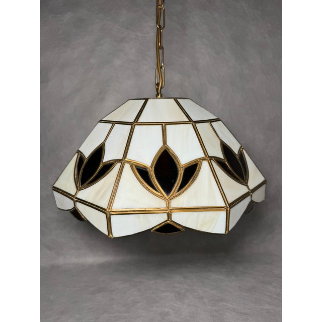 Geometric pendant lamp composed of hand-assembled stained glass panels in milky white tones with a decorative dark leaf...