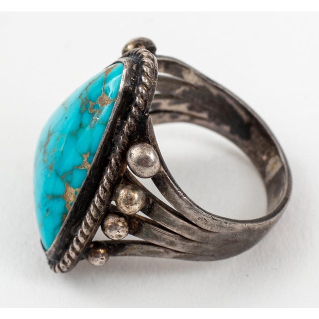 Vintage Native American Navajo silver turquoise ring, comprise of one 21 x 17 mm triangular cabochon-cut turquoise. Ring...