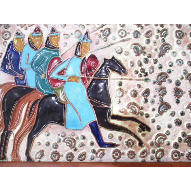 A very well made pottery art tile with colorful horse back riders on a dimpled raised back round surface . Attributed to...
