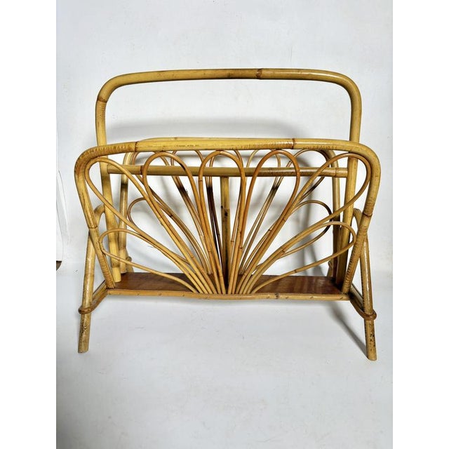 A French magazine rack from the 1960s, crafted from bent rush and rattan, illustrating the artisanal skill and natural...