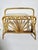A French magazine rack from the 1960s, crafted from bent rush and rattan, illustrating the artisanal skill and natural...