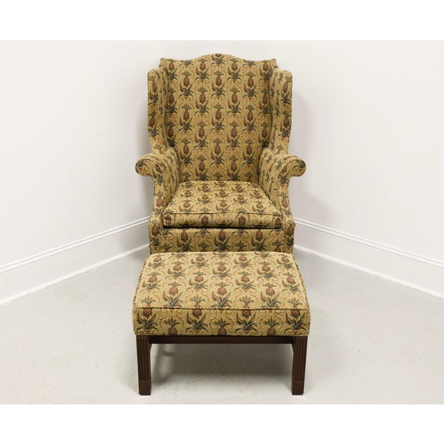 A Chippendale style wing back chair and ottoman by Southwood. Chair has a mahogany wood frame, fabric upholstered in a...