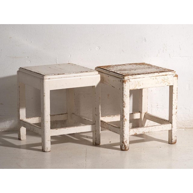 A pair of antique bedside tables in pine wood, with a square top and four tapered legs tied by box stretchers. They...