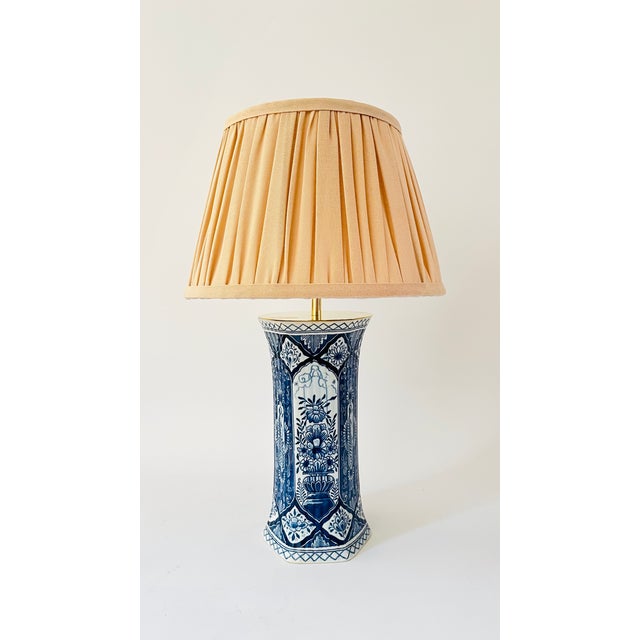 A pair of early 20th century table lamps made from rare antique pillar vases by royal delft. Decorated on an off white...