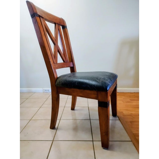 These four chairs are crafted from solid pine wood and decorated with leather strips. They are upholstered in fine black...