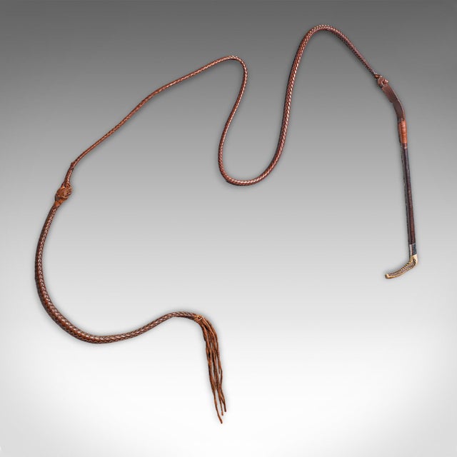 This is a long antique hunting whip. An English, leather and silver collared equestrian accessory by Swaine & Adeney of...