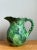 This vintage ceramic pitcher showcases a vibrant green glaze and an intricately detailed leaf motif, epitomizing the...