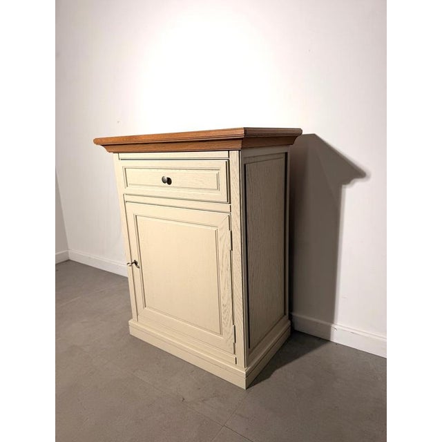 Elegant compact storage cabinet crafted in oak, combining a warm natural wood top with a soft cream-painted body. The...
