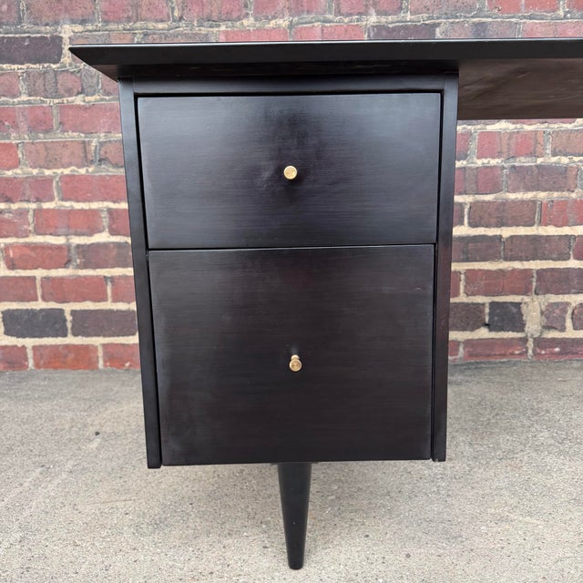 Paul McCobb, featuring a refined ebonized finish paired with minimalist brass pulls. The design highlights McCobb’s...