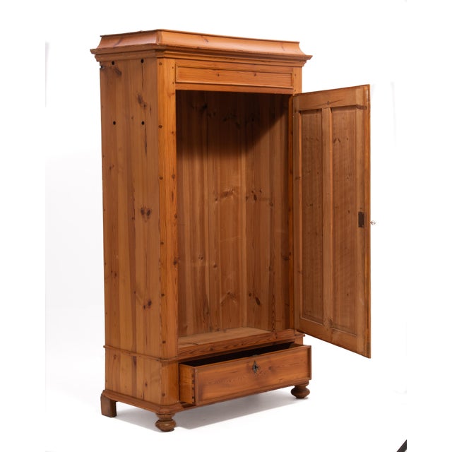 A fantastic Scandinavian pine wardrobe featuring a pagoda style crown on front bun feet, a single two-panel door, a lower...