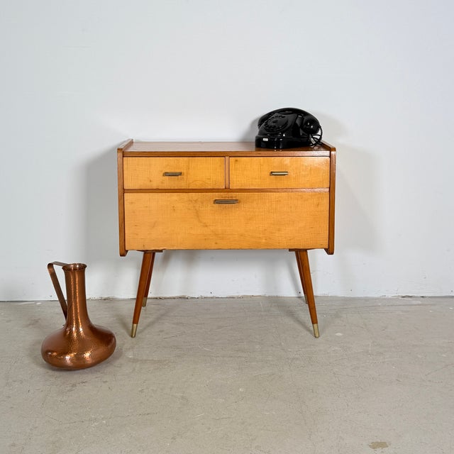 This striking Mid-Century Modern hall cabinet from the 1950s–1960s features a beautiful contrast between the light flamed...