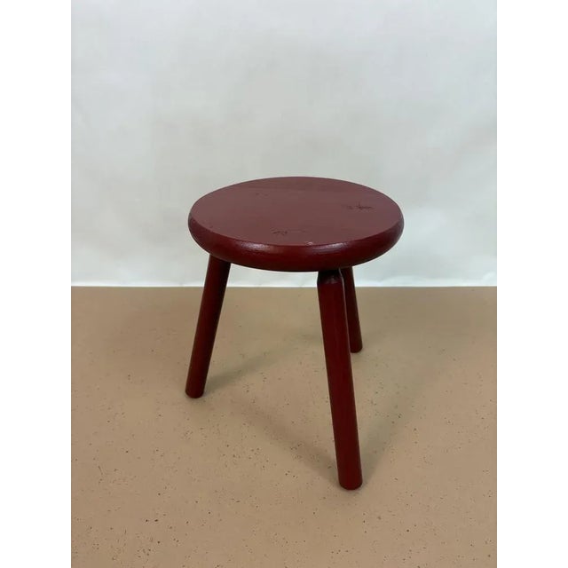 Beautiful solid wood stool from the 1960s, made in the Netherlands. The stool has three legs and is painted red.
