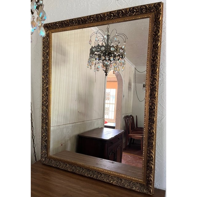 A beautiful, large-scale decorative mirror in the Baroque style, featuring a densely carved gilt wood frame covered with...