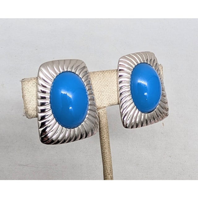 1980s ribbed rhodium plated single cabochon blue rhinestone clip earrings. Marked "TRIFARI©" in a cartouche on the back....