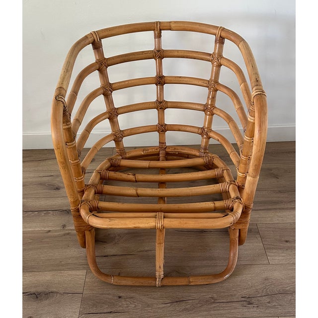 This vintage bent rattan lounge chair features a beautifully sculptural frame with gracefully curved arms and stacked...