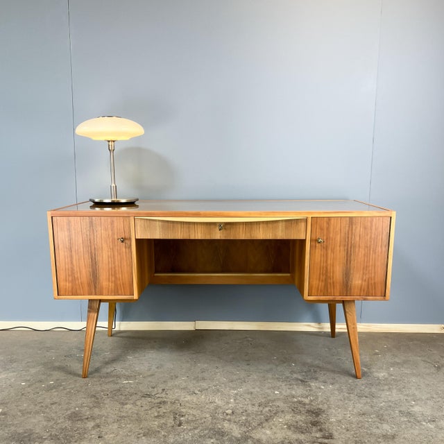 A stunning desk with a unique design that allows for freestanding placement. The front features a cabinet compartment on...