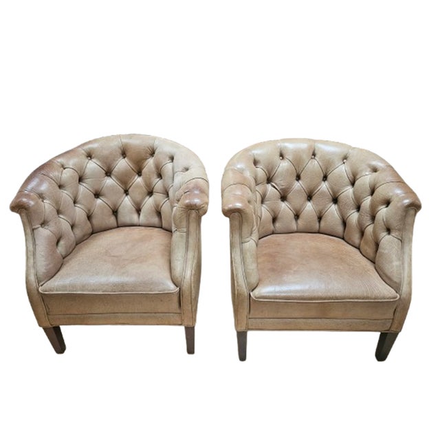 Classic British Chesterfield design with deep button tufting and rolled arms. The chairs feature a warm patinated leather...