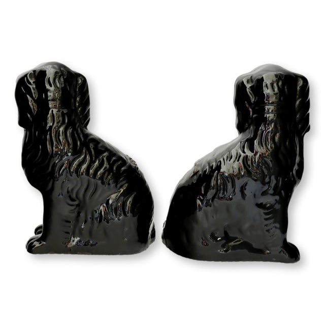 Mid 19th century pair of English Staffordshire “Jackfield” dogs, finished in a deep, lustrous black glaze with gilt collar...