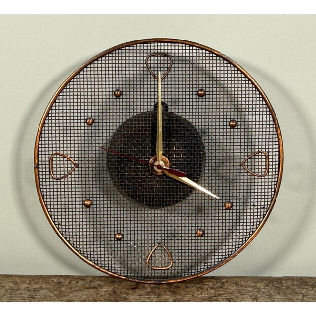 This mid century modern wall clock features a circular copper wire mesh face with a woven mesh center section. The clock...