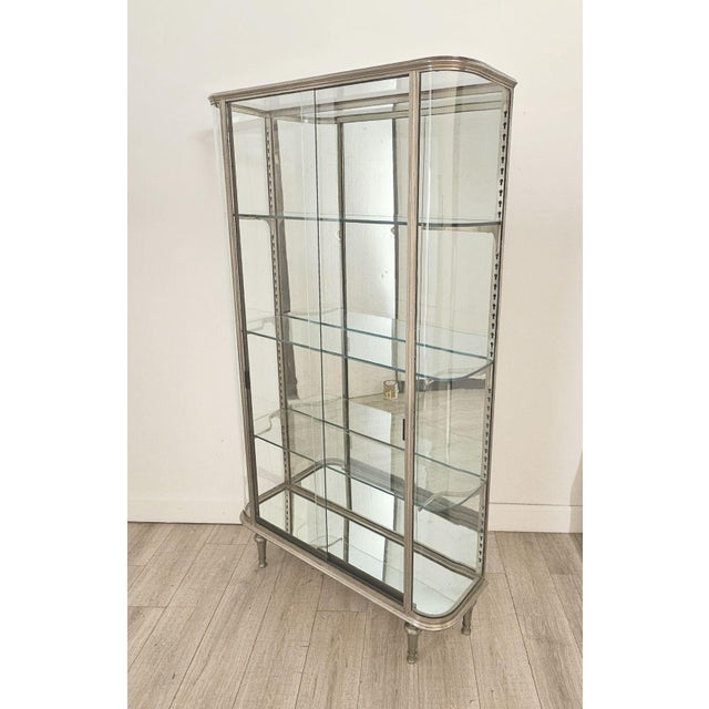 A brushed steel mirrored French display case / vitrine, circa 1920. On turned tapered Louis XVI–style feet. An elegant,...