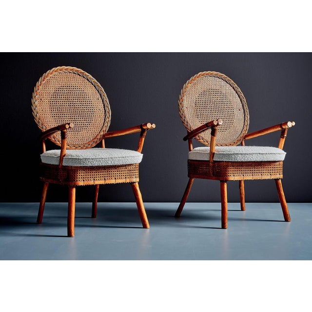 Pair of 1960s lounge chairs with round cane backs, woven rattan seats and sculptural bamboo-style frames. The chairs...
