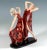 Two graceful dancers in long, low-cut and high-slit red dresses with large floral decorations, posing facing each other...