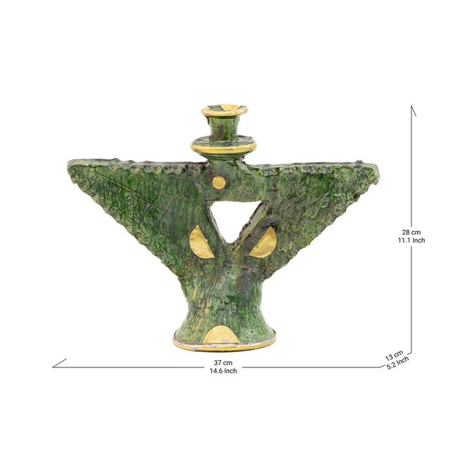 Wide, wing-like arms sweep outward from a sculptural central column in this Tamegroute candle holder, its deep green glaze...