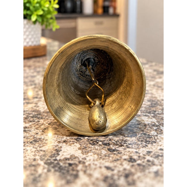 Charming vintage brass hand bell featuring a unique sculptural figural-style handle and classic flared bell shape. Simple...