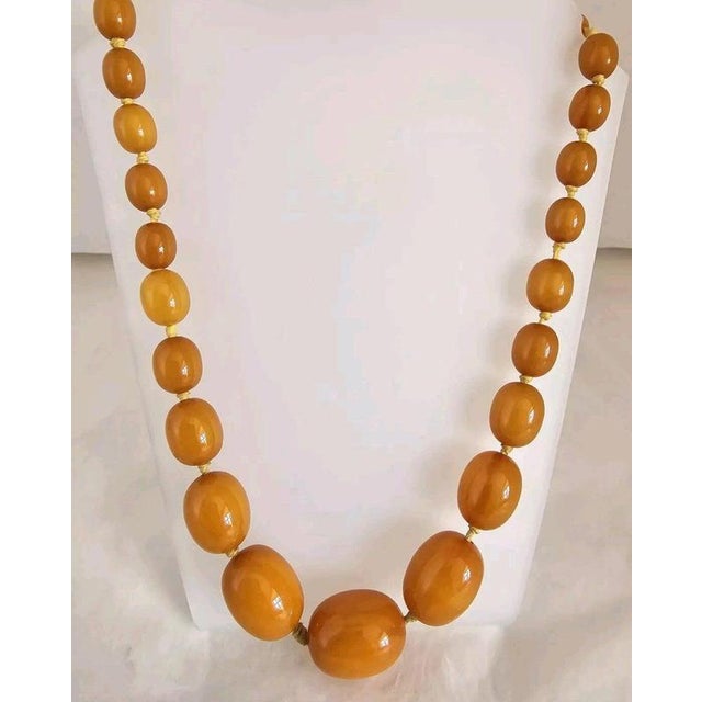 A striking antique graduated bead necklace dating to circa 1930, composed of richly coloured amber-tone beads displaying...
