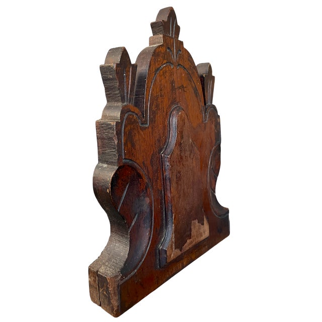 This striking antique carved wooden furniture remnant features bold, symmetrical relief carving with a dramatic crest-like...