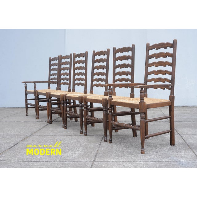 Beautiful vintage set of six English oak ladder back dining chairs with rush seats. There are two captain chairs and four...